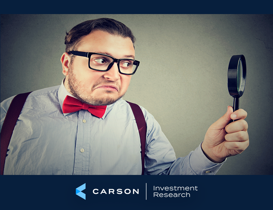 Man in a bow tie and suspenders wearing glasses and holding a magnifying glass