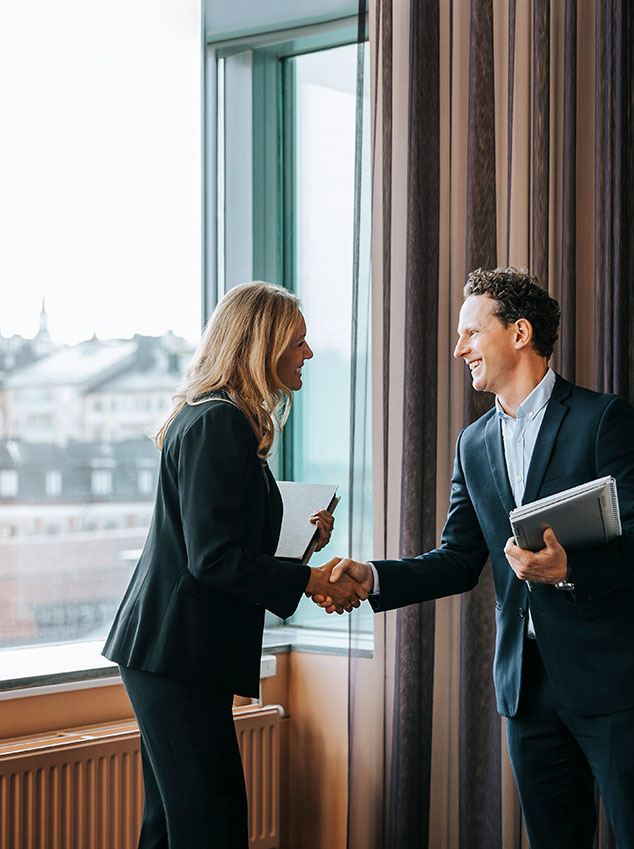 Happy male and female business professionals doing handshake at office